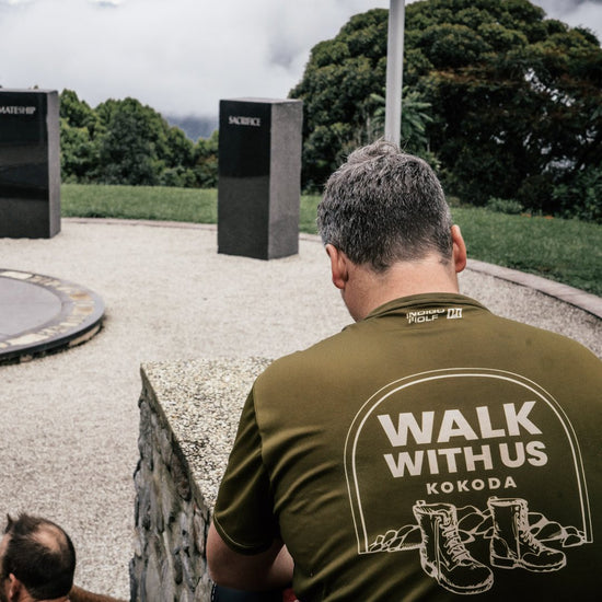 A Walk With Us Kokoda trekker in the team shirt at the Isurava memorial on the Kokoda Track